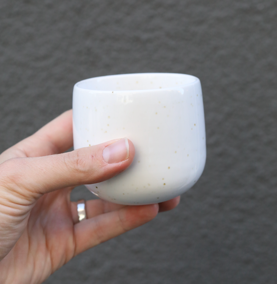 Latte Serra Cup en céramique pour Latte Macchiate tenu à la main sur fond gris.