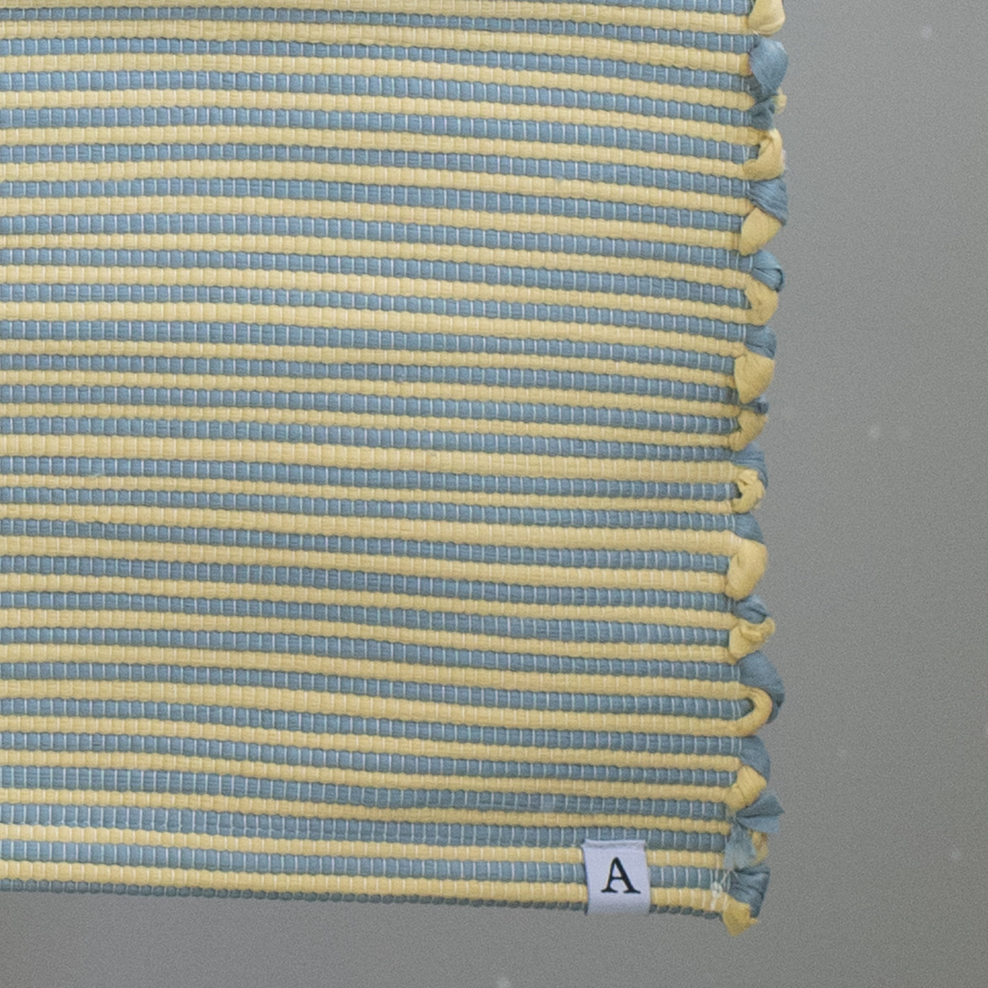 Close-up d'un tapis de salle de bain bicolore à rayures bleues et jaunes