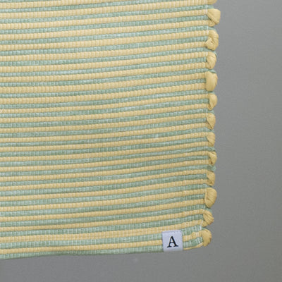 Close-up d'un petit tapis rayé bicolore à rayures jaunes et vertes tissé à la main au Portugal