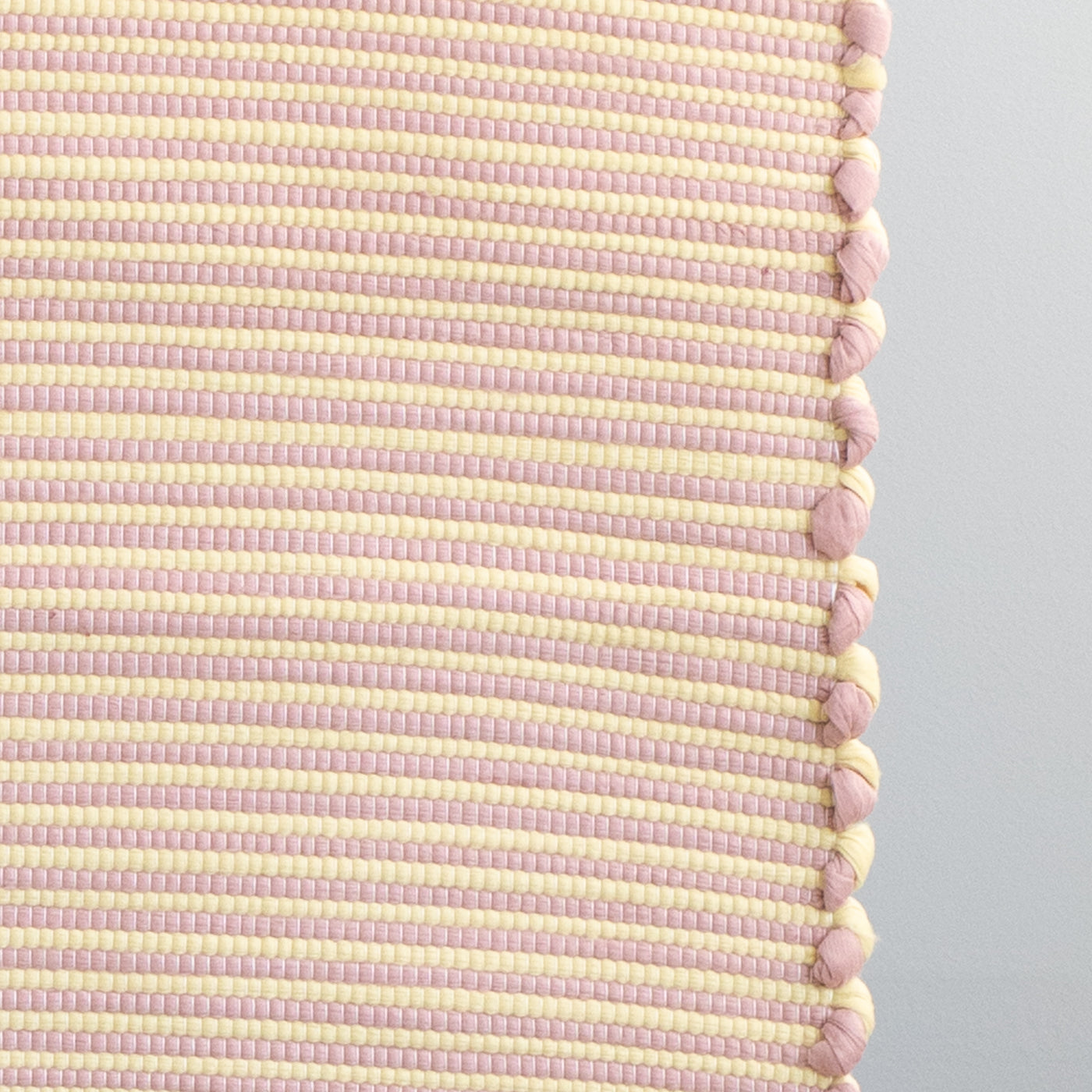 Close-up d'un petit tapis rayé bicolore à rayures jaunes et roses