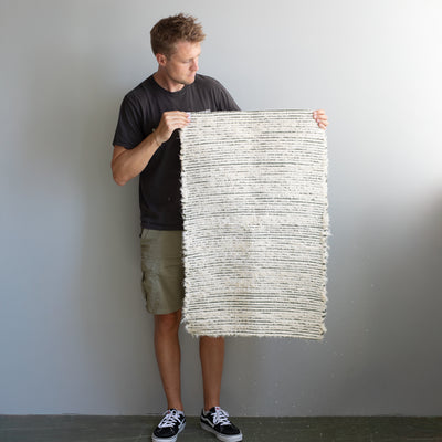 Tapis de bain en éponge tenu debout par une personne avec des rayures vert olive en tissu recyclé produit au Portugal