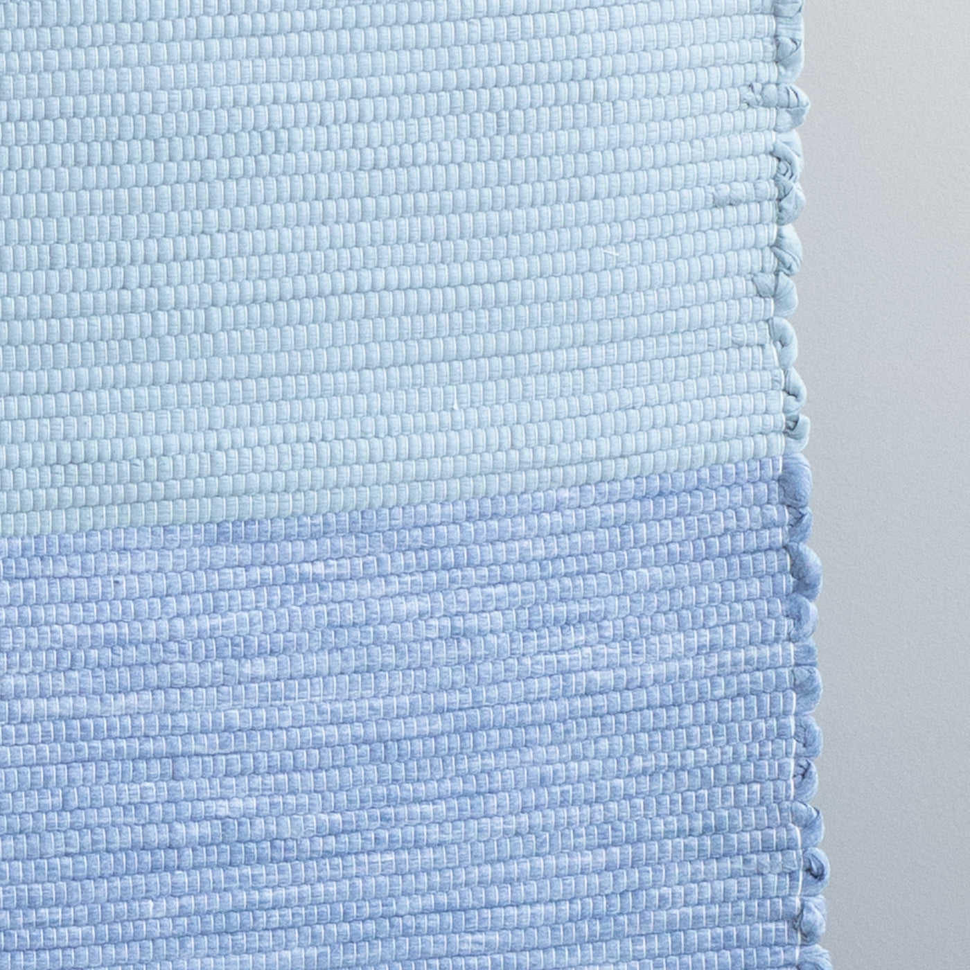 Close-up d'un tapis de bain bleu clair et bleu foncé tissé à la main