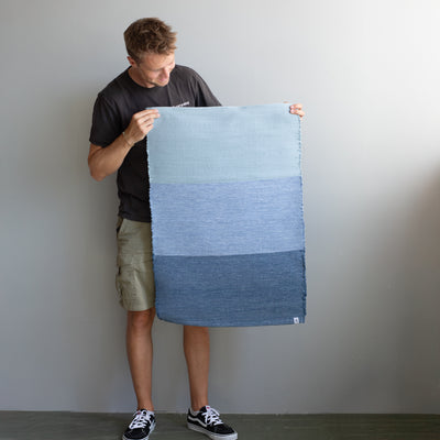 Tapis tenu par une personne avec 3 blocs de couleurs de différents tons de bleu
