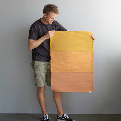 Tapis de pieds tenu par une personne en trois couleurs allant de l'orange clair à l'orange foncé