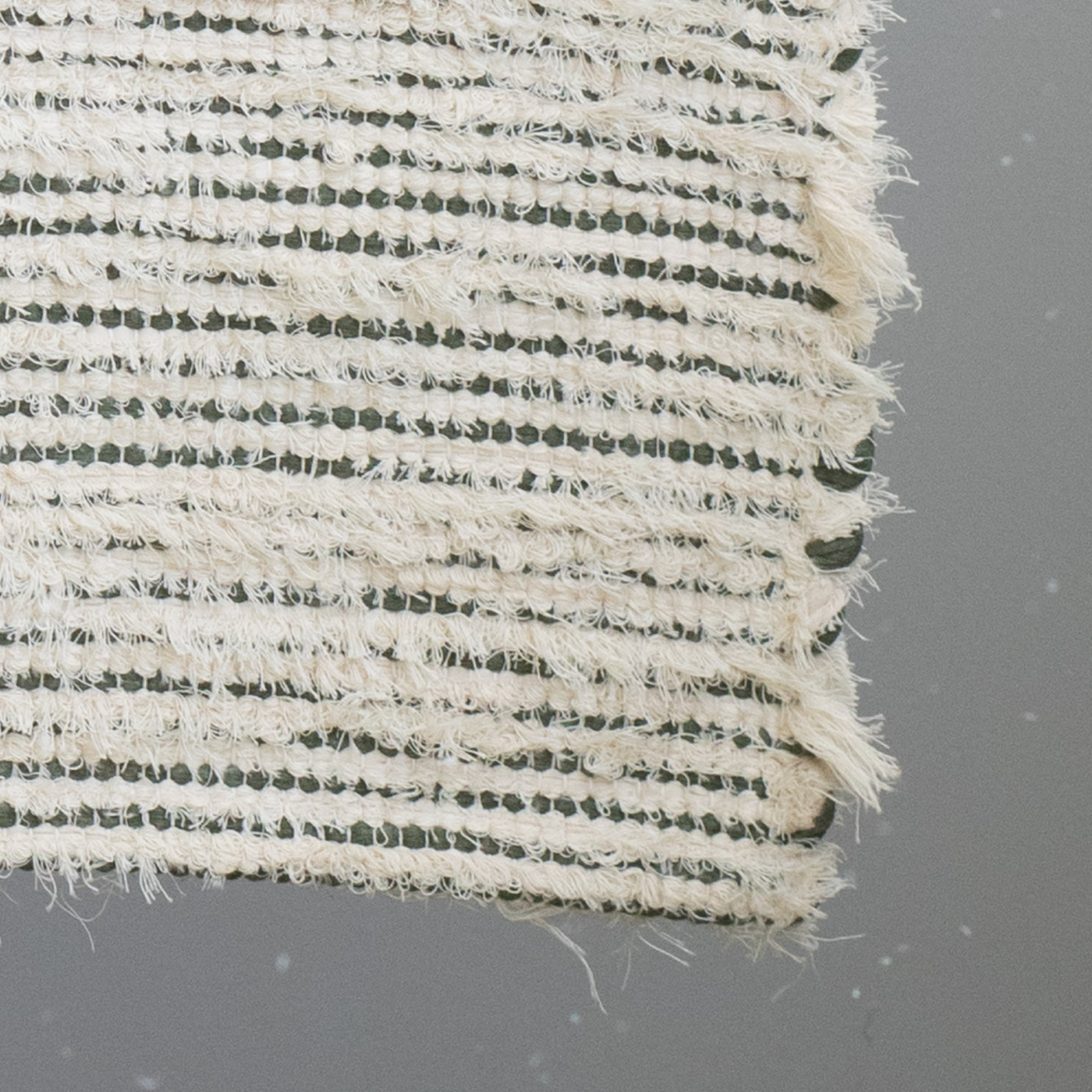 Closeup d'un tapis de salle de bain rayé avec du coton vert olive et du tissu éponge blanc 