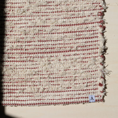 Closeup d'un petit tapis 60x80cm rayé avec du coton couleur pêche et du tissu éponge blanc dans la lumière du soleil