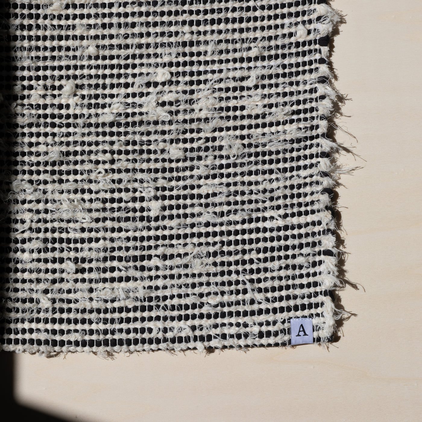 Closeup d'un petit tapis 60x80cm rayé avec du coton noir et du tissu éponge blanc dans la lumière du soleil