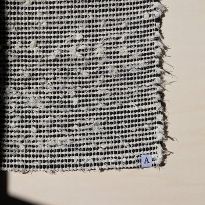 Closeup d'un petit tapis 60x80cm rayé avec du coton noir et du tissu éponge blanc dans la lumière du soleil