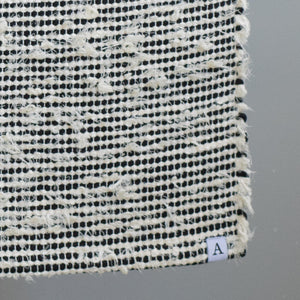 Closeup d'un tapis de salle de bain rayé avec du coton noir et du tissu éponge blanc 