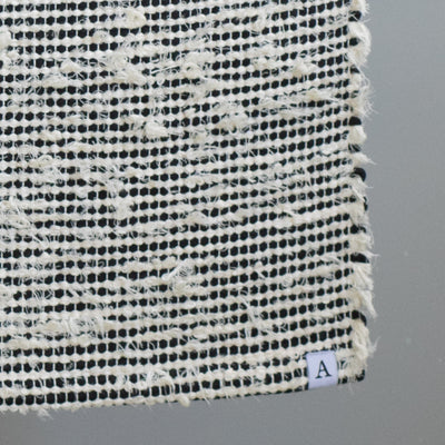 Closeup d'un tapis de salle de bain rayé avec du coton noir et du tissu éponge blanc 