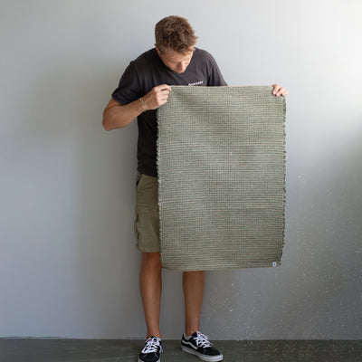 60x90cm petit tapis tenu par une personne en vert rayé avec du jute tissé à la main au Portugal