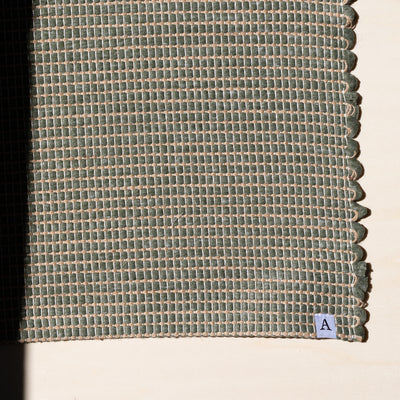 Close-up d'un petit tapis 60x90cm en vert avec du jute entrelacé tissé à la main en coton upcycling au Portugal