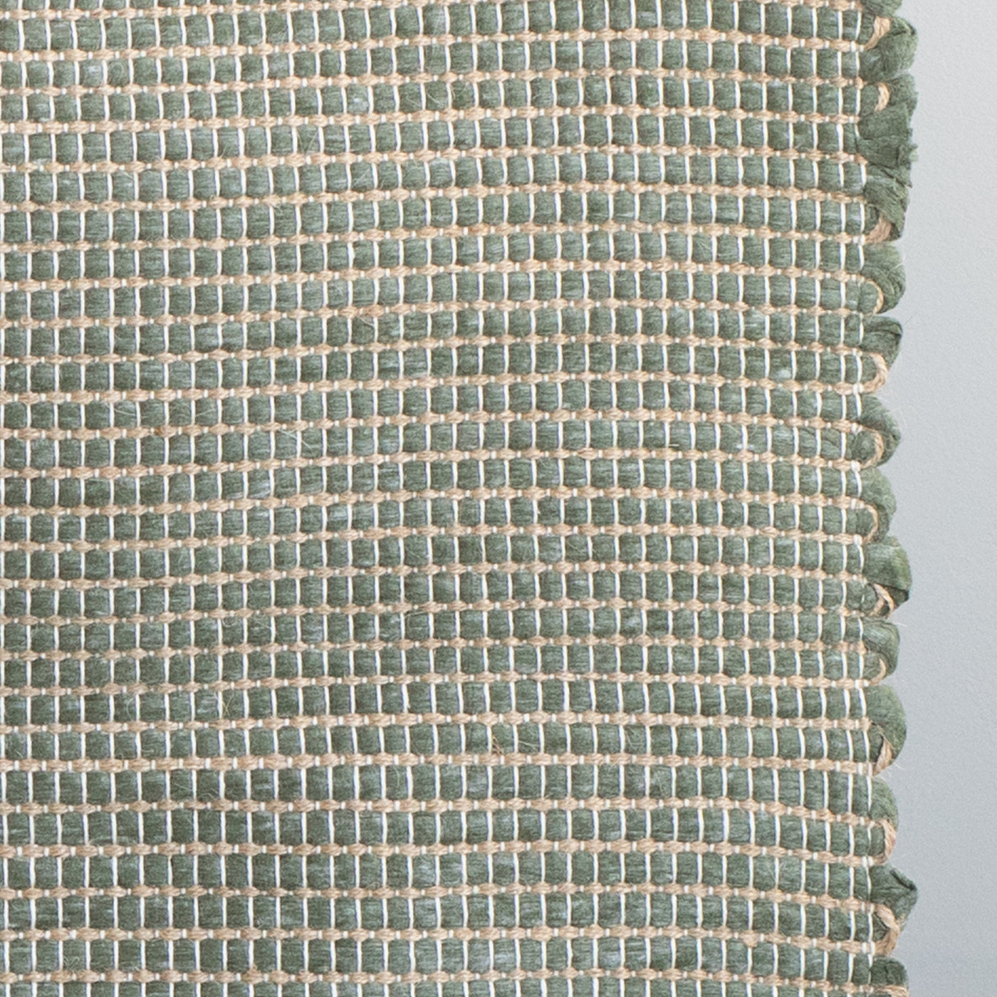 Close-up d'un tapis de bain vert rayé de jute fabriqué à partir de chutes de laine provenant de l'industrie textile et tissé à la main au Portugal