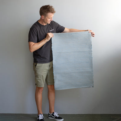 60x90cm petit tapis tenu par une personne en bleu clair rayé avec du jute tissé à la main au Portugal