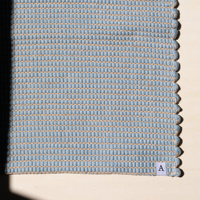 Close-up d'un petit tapis 60x90cm en bleu clair avec du jute entrelacé tissé à la main en coton upcycling au Portugal