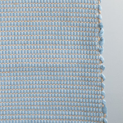 Closeup d'un tapis de salle de bain bleu clair rayé de jute, fabriqué à partir de chutes de laine provenant de l'industrie textile et tissé à la main au Portugal.