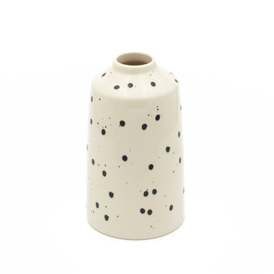 Vase de fleurs à pois noirs avec couleur beige dégagé sur fond blanc