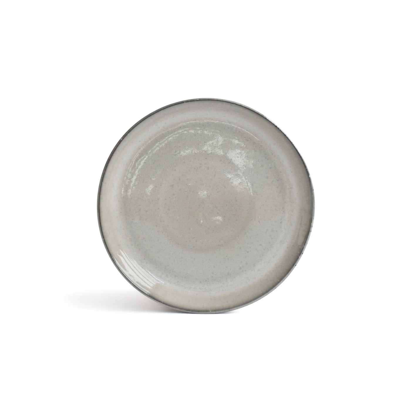 La petite assiette gris clair avec un bord gris foncé se détache sur un fond blanc.