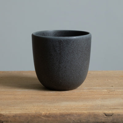 Gobelet à cappuccino noir mat sur une table en bois