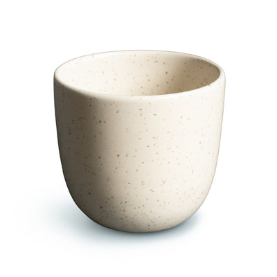 Tasse à café beige avec de fines éclaboussures sur fond blanc détaché
