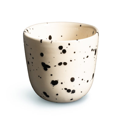 Tasse à café beige à pois noirs sur fond blanc détaché