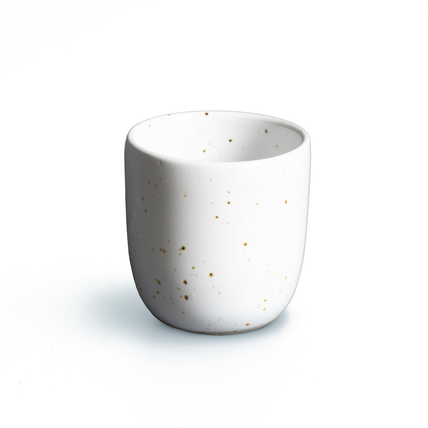 Tasse à expresso sans anse en blanc avec des éclaboussures dorées sur fond blanc dégagé