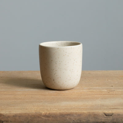 Gobelet à espresso beige mat sur une table en bois, vu de face