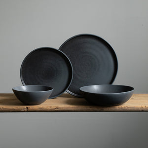 Set de vaisselle complet en noir mat comprenant une grande et une petite assiette, un bol à muesli et une assiette à pâtes, le tout fabriqué en grès au Portugal.