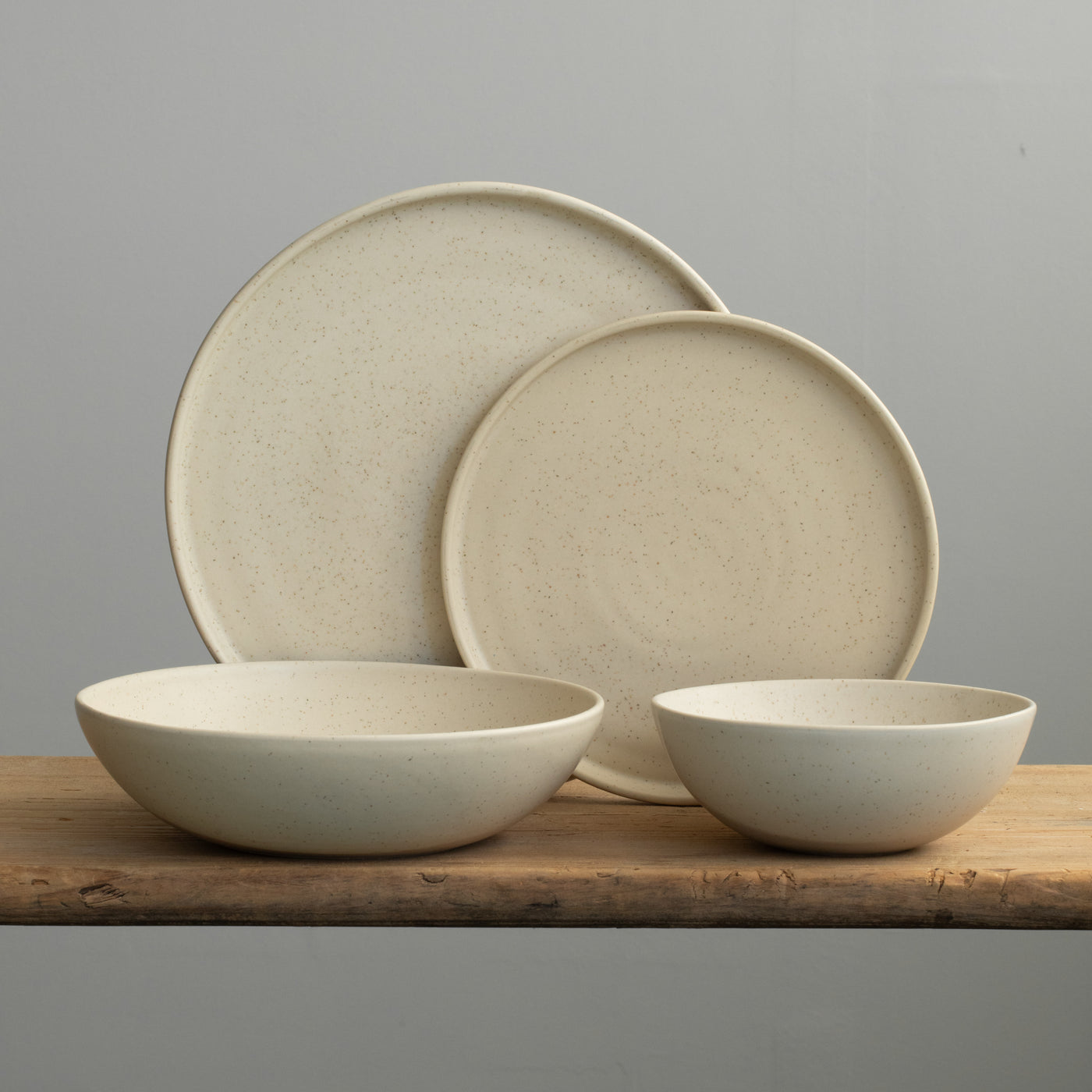 Set de vaisselle complet en émail beige avec une grande et une petite assiette, une assiette creuse à pâtes et un bol à muesli