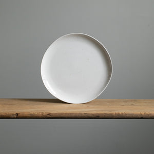 Grande assiette de plat principal de couleur blanche avec de fines éclaboussures de couleur dorée debout en vue frontale