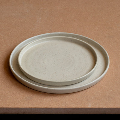 La petite assiette repose dans la grande assiette Les deux ont un bord droit et sont beige mat
