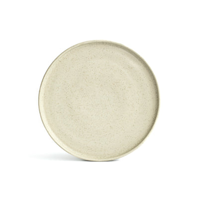 Une grande assiette en beige matte speckled, avec un bord incliné, sur un fond blanc.