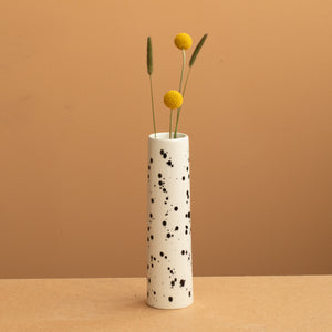 petit vase étroit de couleur beige avec des points noirs avec des fleurs jaunes.