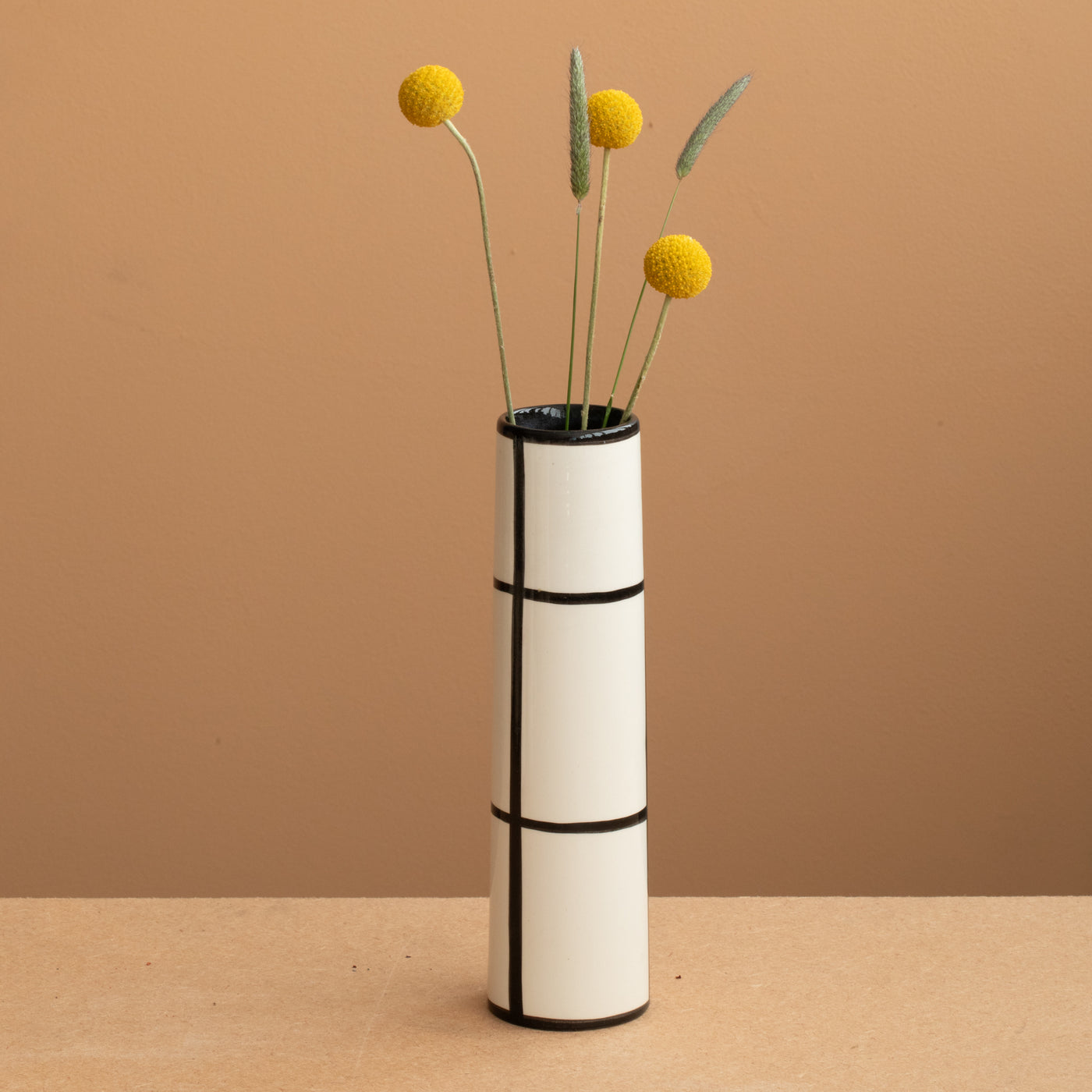 Vase fin de couleur blanche à carreaux noirs et fleurs jaunes et vertes