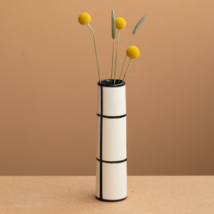 Vase fin de couleur blanche à carreaux noirs et fleurs jaunes et vertes