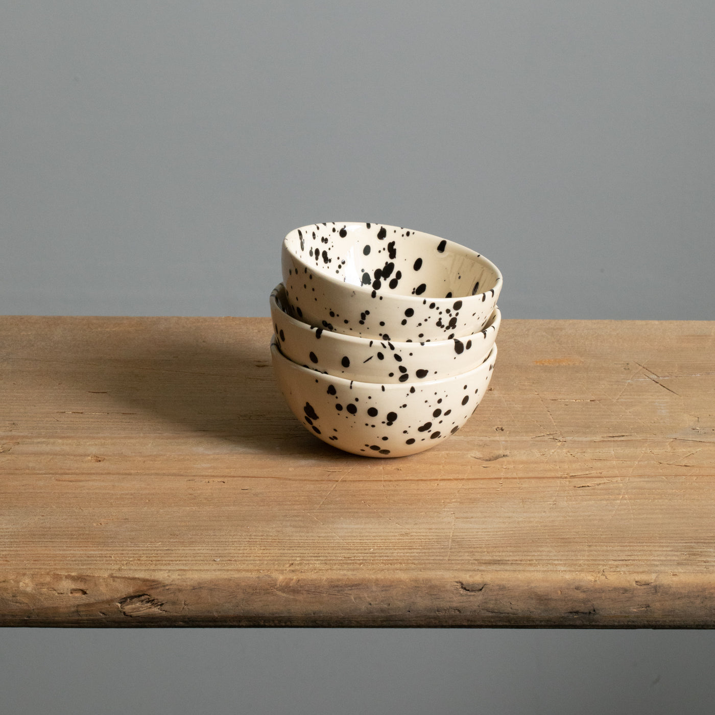 Trois petits bols à goûter empilés en couleur crème avec des touches de noir.