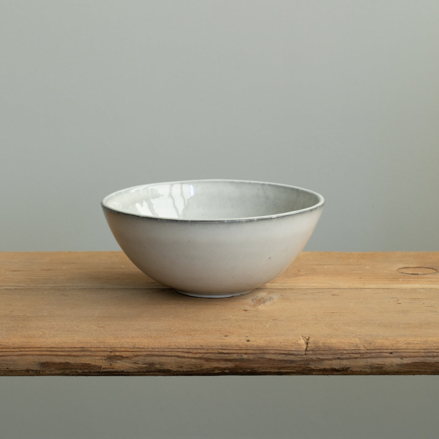 Un bol à déjeuner gris clair avec un bord légèrement ouvert vers l'extérieur sur une table en bois