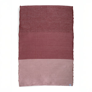 Tapis divisé en trois blocs de couleur, du bordeaux au rose, sur fond blanc.