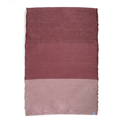 Tapis divisé en trois blocs de couleur, du bordeaux au rose, sur fond blanc.