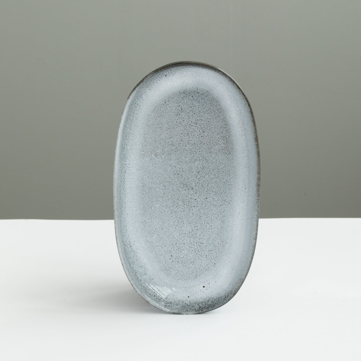 Assiette ovale de 22 cm de long, parfaite comme soucoupe ou assiette à hors-d'œuvre, en émail bleu chiné réactif.