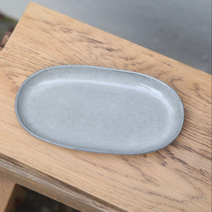 Assiette-soucoupe ovale gris clair de 22 cm de long vue d'en haut sur une planche en bois