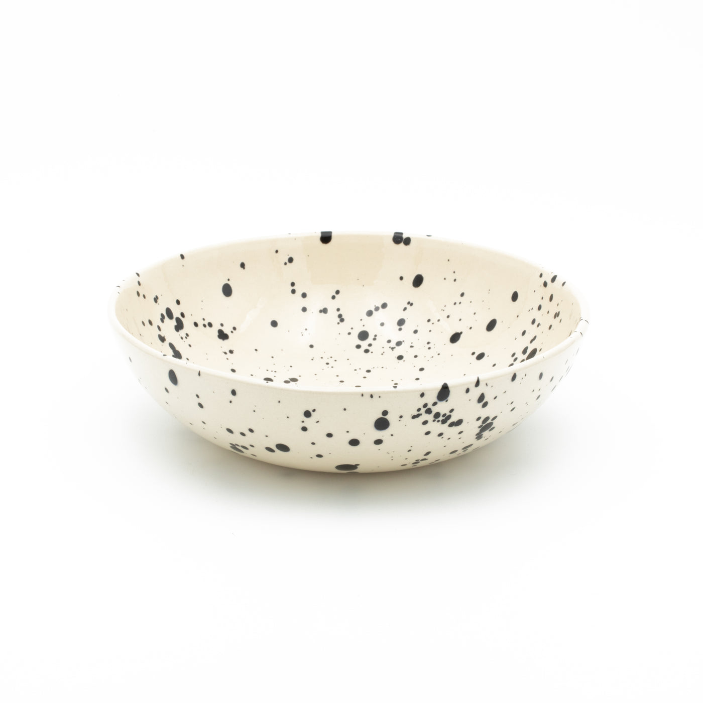 Assiette ronde pour pâtes en couleur crème avec des éclaboussures de peinture noire sur un fond blanc dégagé