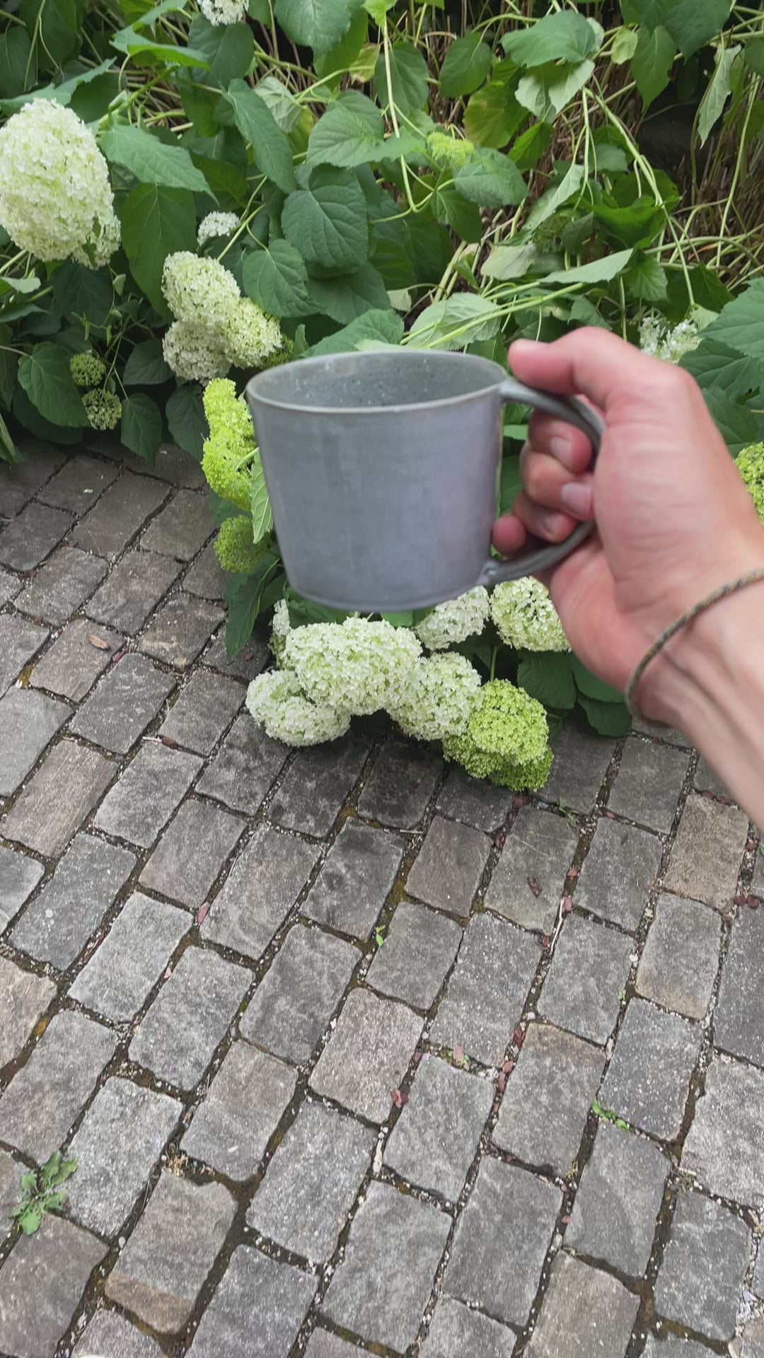 Grande tasse à thé avec anse, tournée dans tous les sens à la lumière du jour pour faire ressortir l'émail réactif gris-bleu.