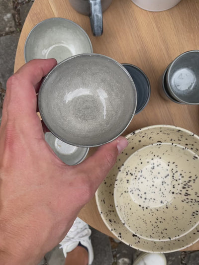 Le petit Snack Bowl gris clair est présenté sous tous les angles. Le bol a une forme organique et un glaçage Midnight Grey brillant.
