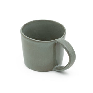 La grande tasse à thé gris foncé avec anse en grès se détache sur un fond blanc. 