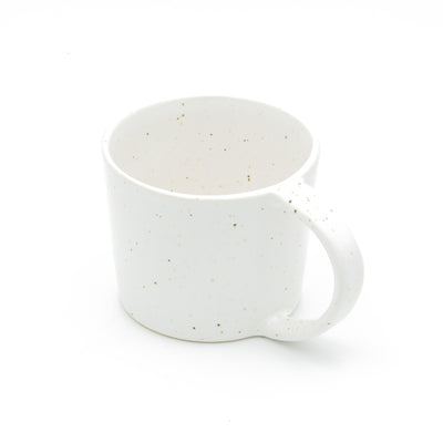 Grande tasse à thé blanche finement mouchetée d'or avec une grande anse pour toute la main sur fond blanc