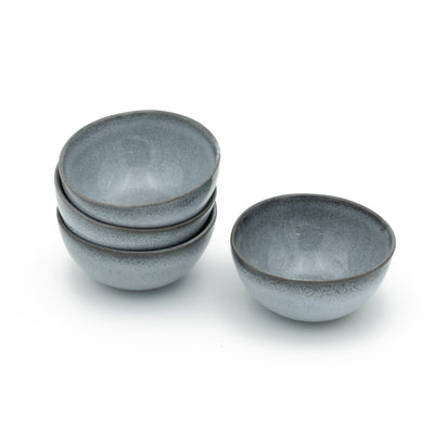 Quatre petits snack bols bleus empilés les uns sur les autres avec un fond blanc